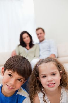 Children sitting in the living room with their parents behind them