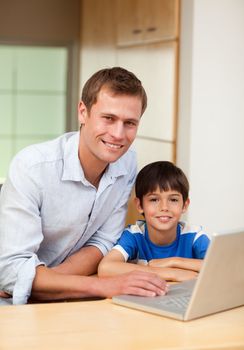 Father and son with notebook in the kitchen