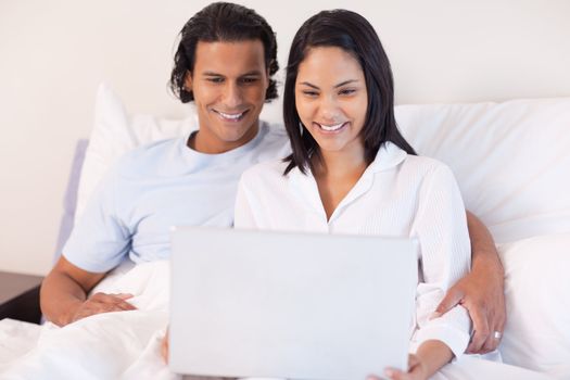 Young couple sitting on the bed with their laptop