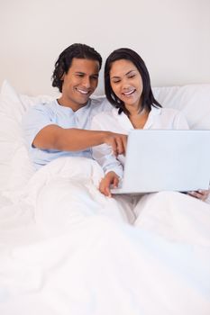 Young couple sitting on the bed with their notebook