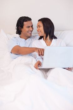 Young couple sitting on the bed surfing the internet