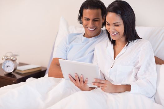 Young couple sitting on the bed using tablet pc
