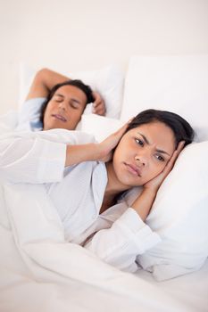 Young woman covering her ears to block her boyfriends snoring