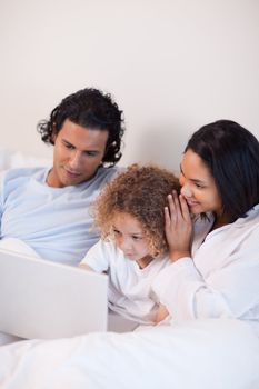 Young family sitting on the bed with laptop