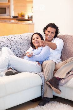 Cheerful young couple watching television together