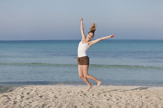 Girl young cheerful woman jumping in the air on the beach in the sand in the morning on the sea in summer vacation