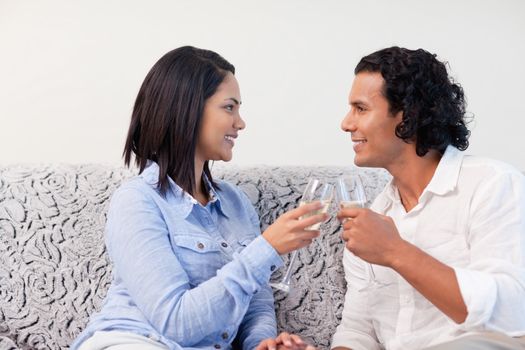 Young couple having sparkling wine on the sofa