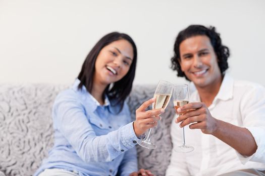 Young couple celebrating with sparkling wine on the couch