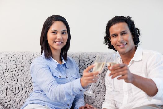 Young couple celebrating with sparkling wine on the sofa