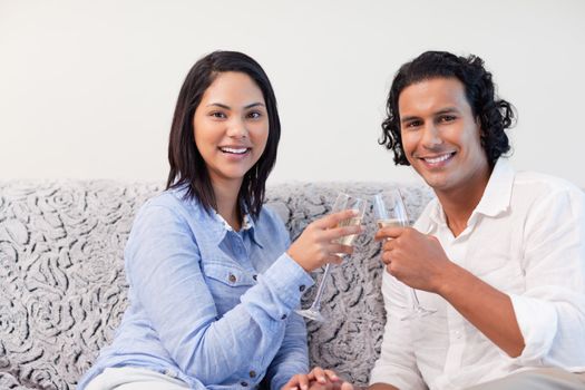 Young couple having sparkling wine on the sofa