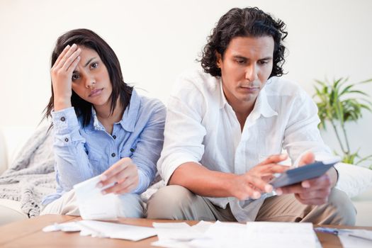 Frustrated young couple doing their calculations in the living room