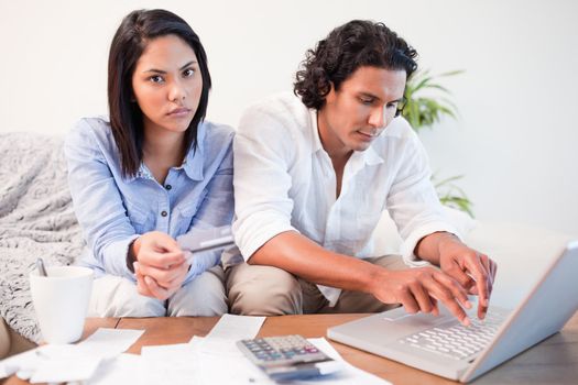Young couple checking their bank accounts online in the living room