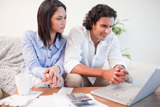 Young couple sitting in the living room doing online banking