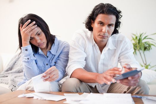 Frustrated young couple checking their bills in the living room