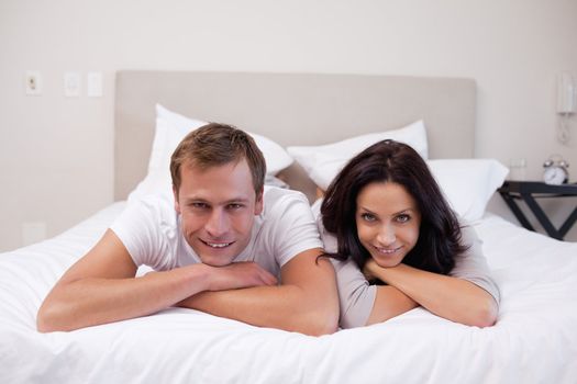 Happy young couple laying on the bed together