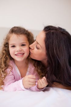 Young mother giving her little daughter a kiss