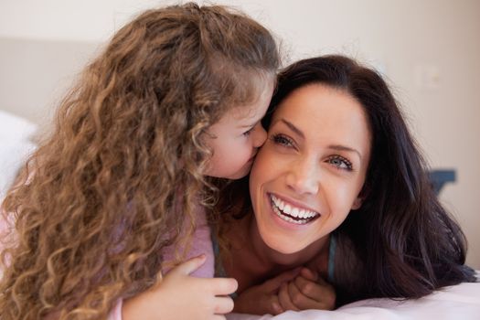 Little daughter giving her mother a kiss on the cheek