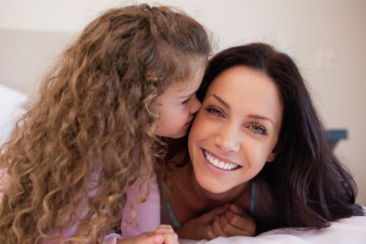Little daughter giving her young mother a kiss