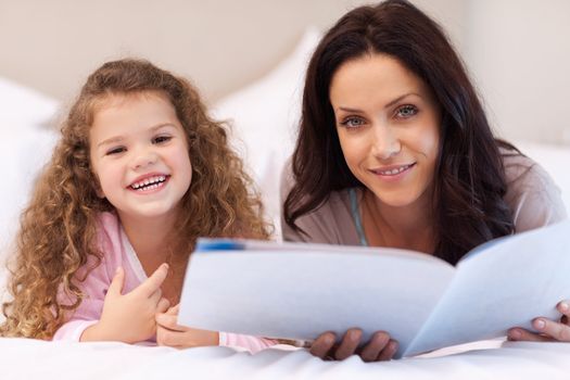 Young mother and daughter enjoying reading together
