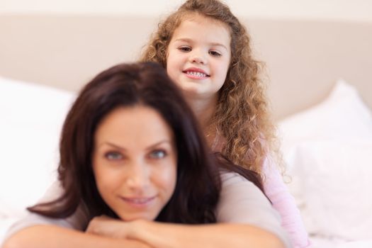 Smiling little girl sitting on her mothers back