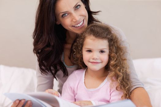 Young mother reading a book with her little daughter