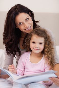 Smiling young mother reading a bedtime story with her little daughter