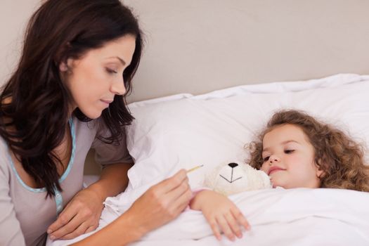 Young mother taking her daughters temperature