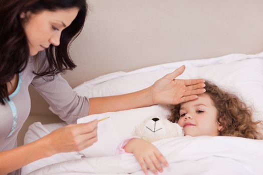Young mother measuring her daughters temperature