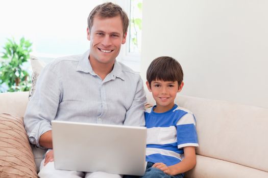 Young father and son with laptop on the sofa