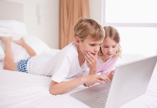 Children using a laptop in a bedroom
