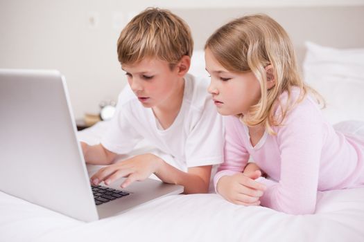 Cute children using a laptop in a bedroom