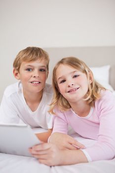 Portrait of children using a tablet computer in a bedroom