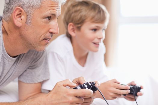Father playing video games with his young son in a bedroom