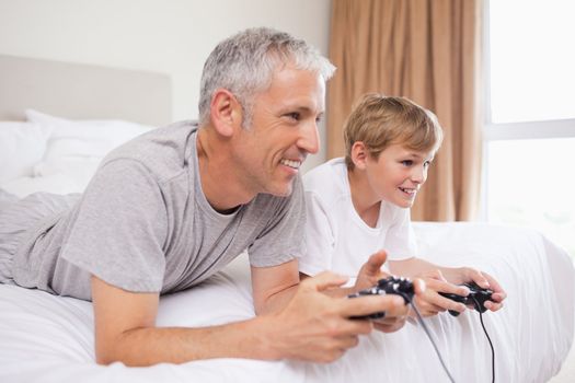 Happy father and his son playing video games in a bedroom