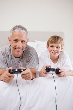 Portrait of a boy and his father playing video games in a bedroom