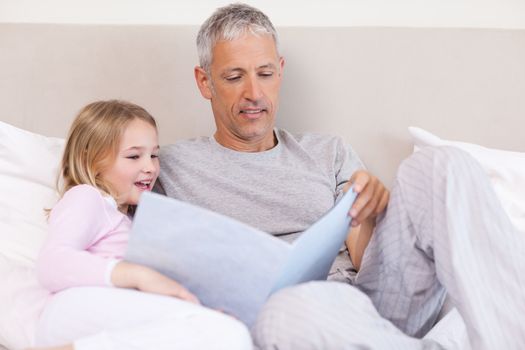 Father reading a story to his daughter in a bedroom