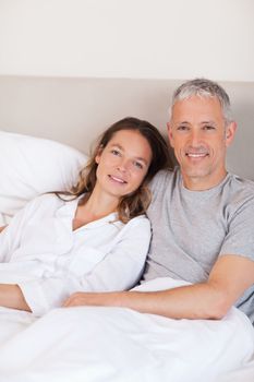 Portrait of a couple lying on a bed while looking at the camera