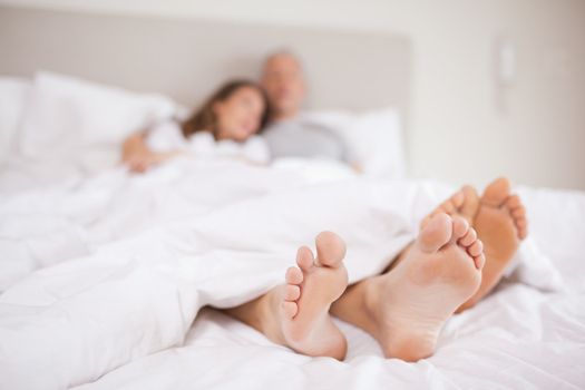 Lovely couple lying in a bed with the camera focus on their feed