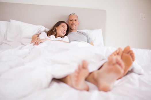 Charming couple lying in a bed while hugging
