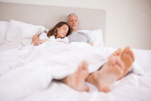Couple sleeping in their bedroom with their eyes closed
