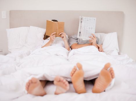 Playful couple reading in their bedroom