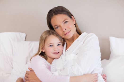 Mother and daughter hugging in a bedroom