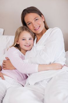 Portrait of a mother and her daughter hugging in a bedroom