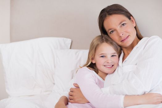 Mother and her daughter hugging in a bedroom