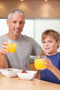 Portrait of a cute boy and his father having breakfast in a kitchen