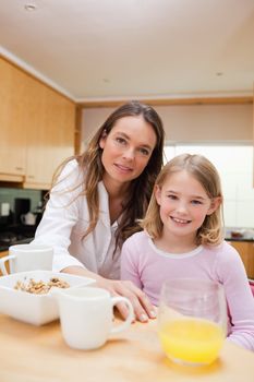 Portrait of a happy mother and her daughter having breakfast in a kitchen