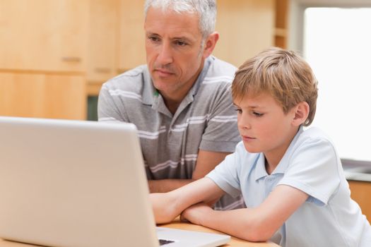 Boy and his father using a laptop in a kitchen