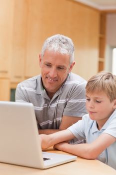 Portrait of a boy and his father using a notebook in a kitchen