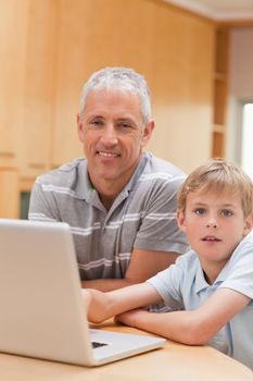 Portrait of a boy and his father using a laptop in their kitchen