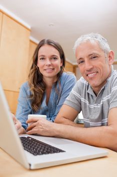 Portrait of a couple using a laptop while having tea in their kitchen